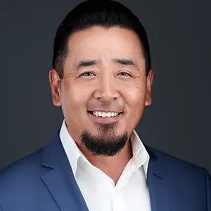 Smiling businessman with beard wearing navy blazer in professional studio headshot portrait.