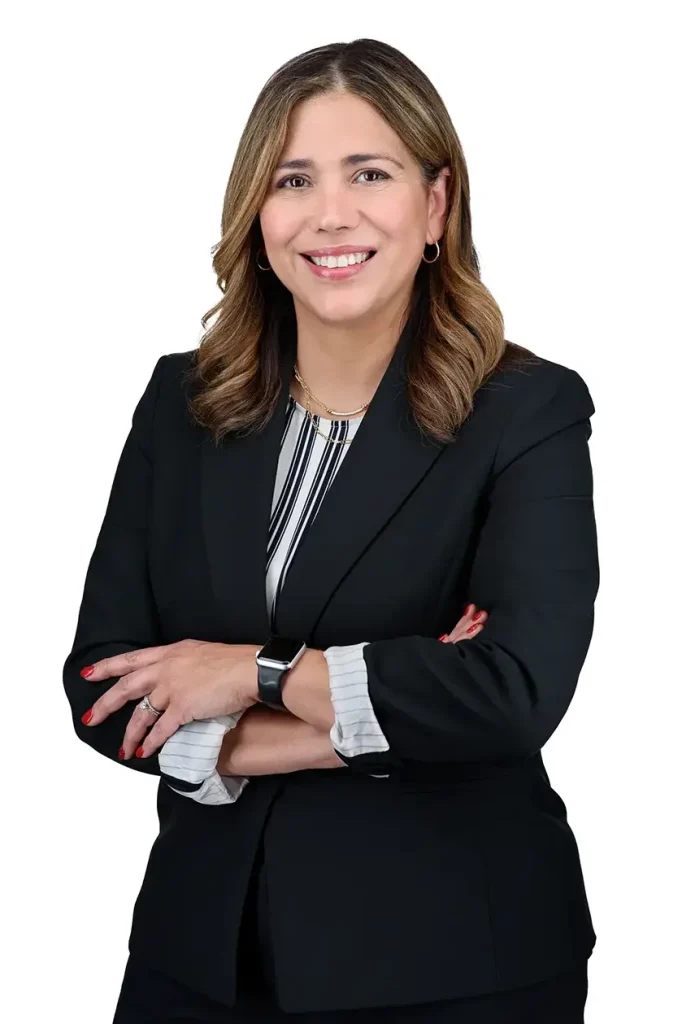 Smiling professional businesswoman in navy blazer, corporate headshot on white background.